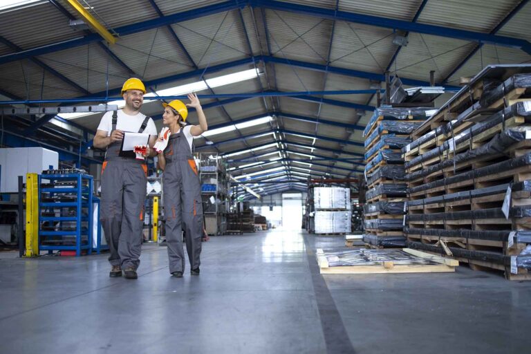 Factory workers in work wear and yellow helmets walking through